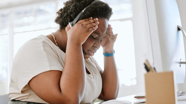 Anxious female call center telemarketing agent feeling pressure and headache while working in a dem.